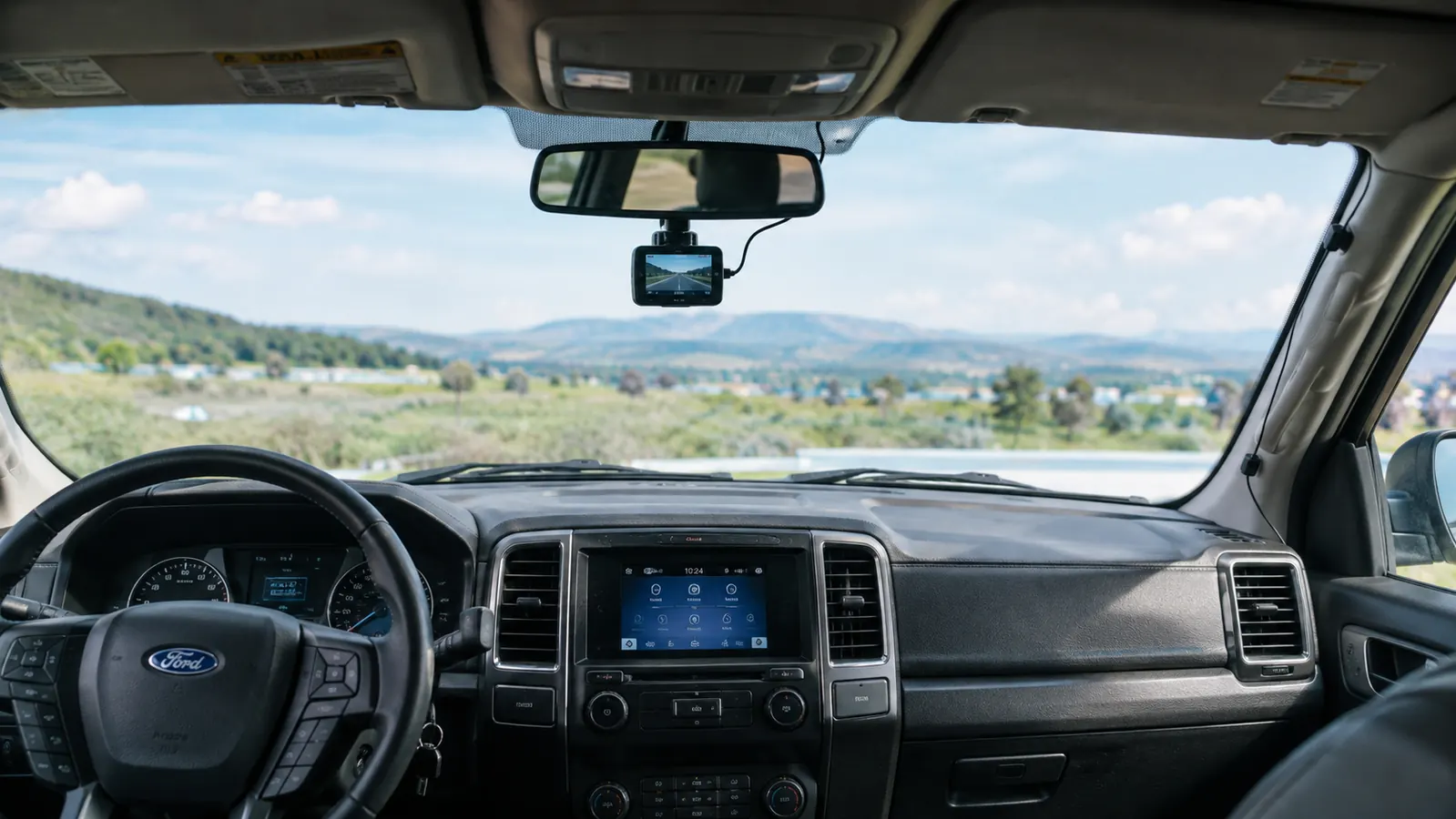 A dash cam mounted behind the rearview mirror with the cable routed down to the cigarette lighter port